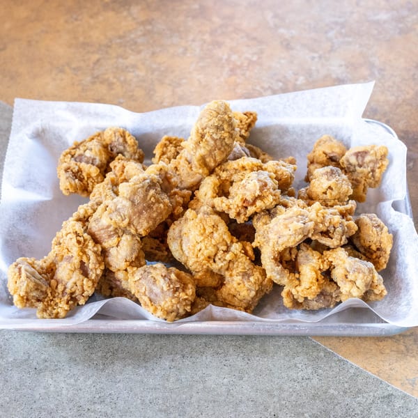 Crispy fried chicken gizzards in a metal tray lined with white parchment paper.